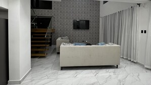 Ein modernes Wohnzimmer mit einer Couch, einem Flachbildfernseher und einer Treppe, die eine weitere Ebene hinaufführt.