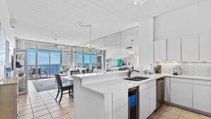 Une cuisine moderne dotée d’un grand îlot central, d’un lave-vaisselle et offrant une vue sur l’extérieur.