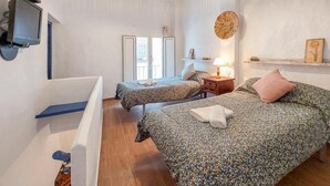 A bedroom with two beds, a TV, a wooden floor, and a window. - 2 bedroom luxurious home in El Gastor (El Gastor)