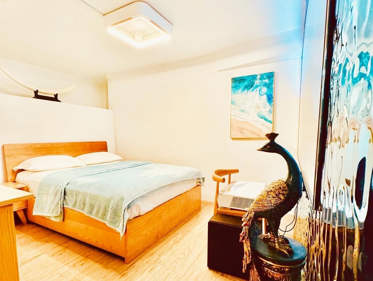 A modern bedroom with a wooden bed, a nightstand, a lamp, and a wall-mounted painting.