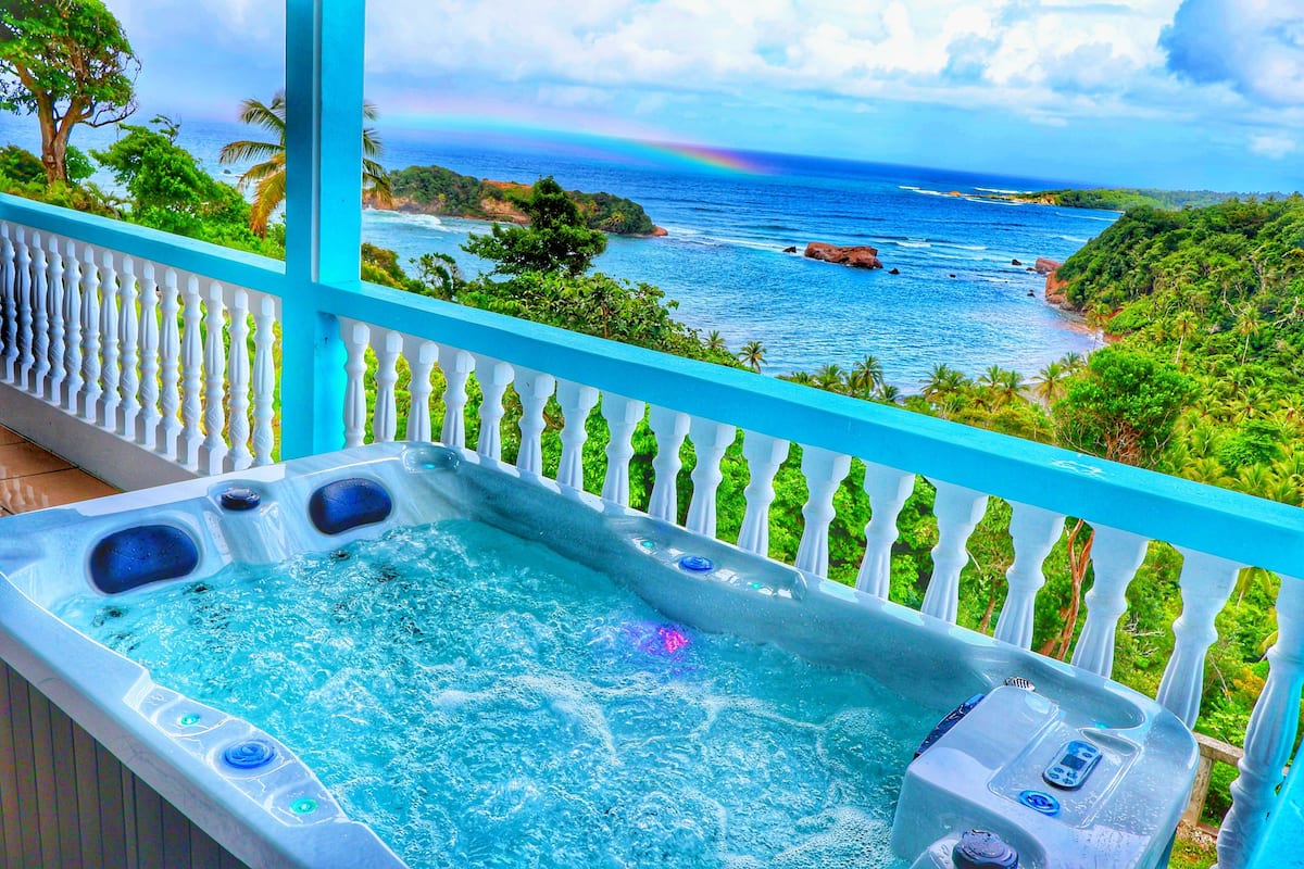 A hot tub with a view of the ocean and a rainbow.