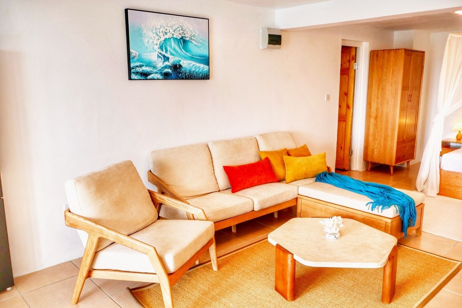A living room with a beige sofa, a wooden coffee table, and a colorful throw blanket.