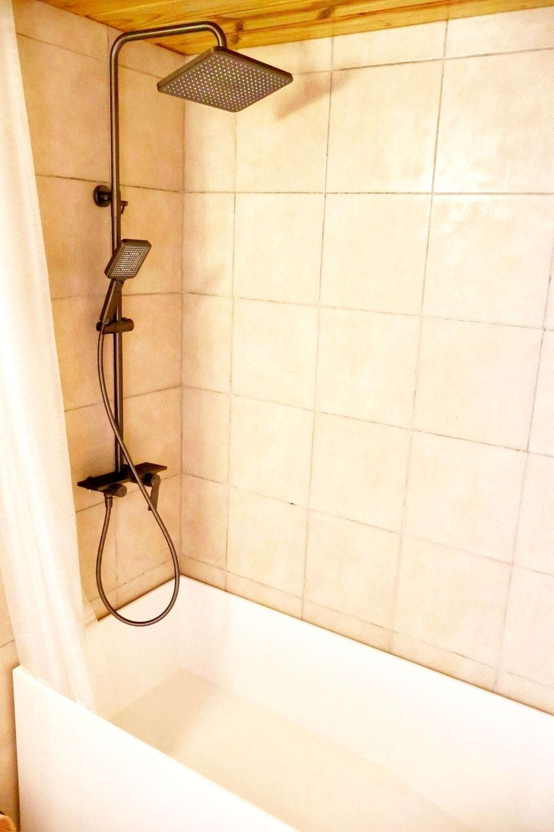 A shower with a handheld showerhead and a fixed showerhead mounted on the wall.
