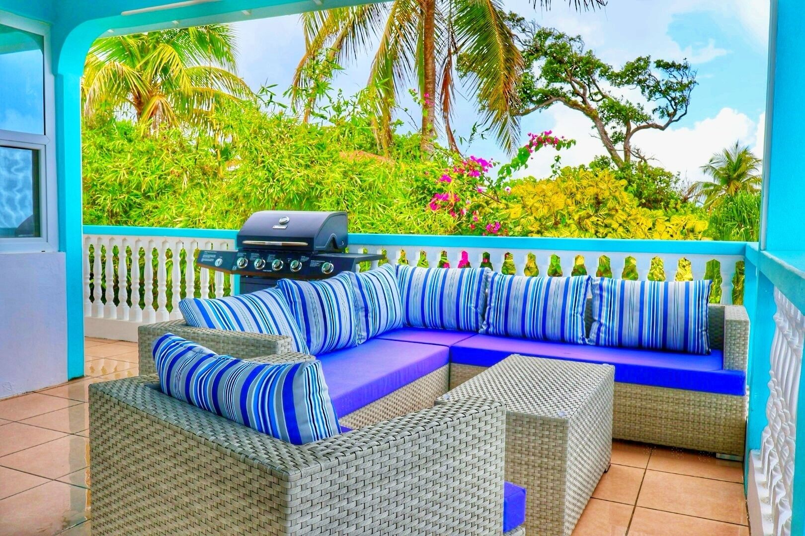A covered patio with wicker furniture and a grill.