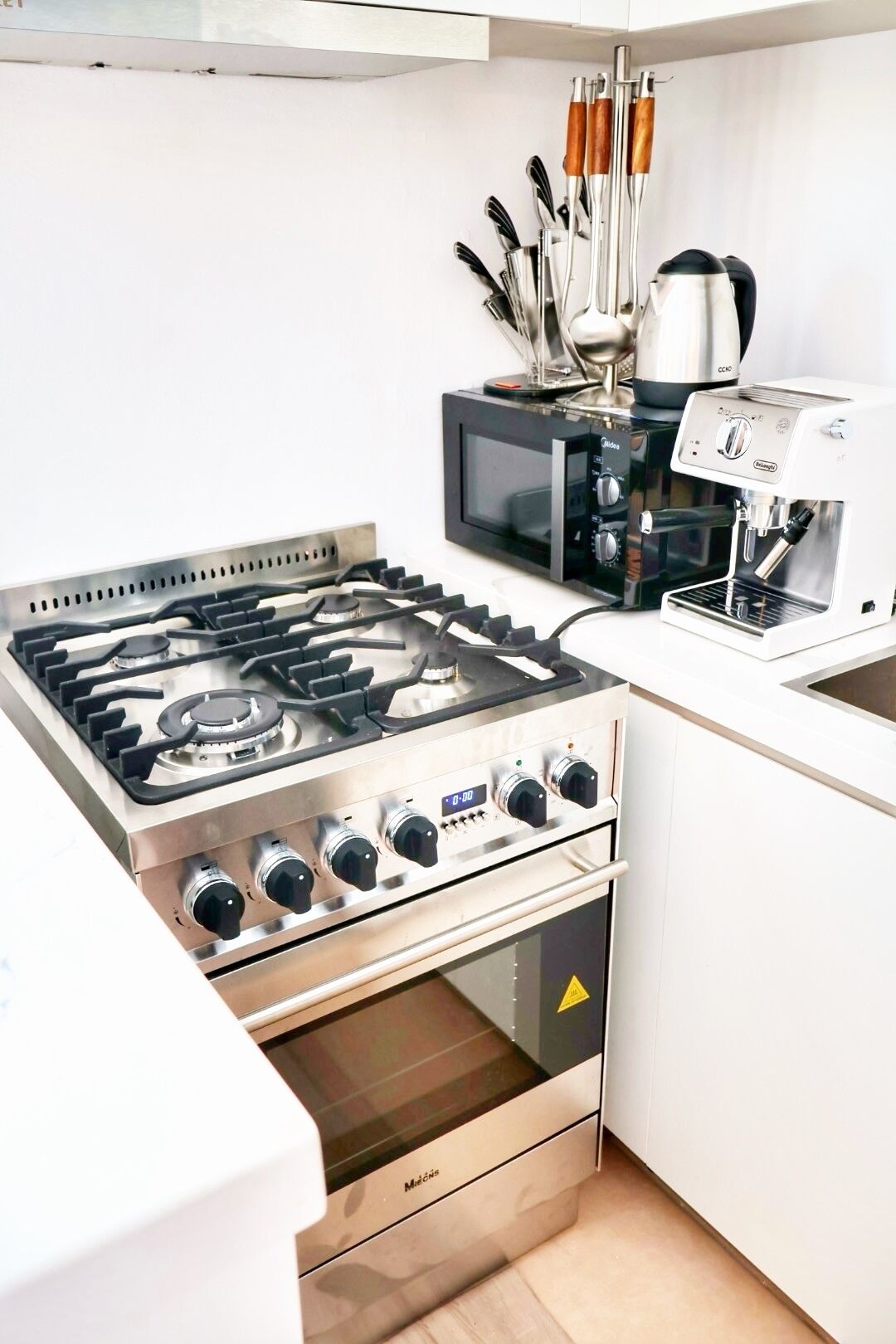 Een keuken met een gasfornuis, oven, magnetron en koffiezetapparaat.