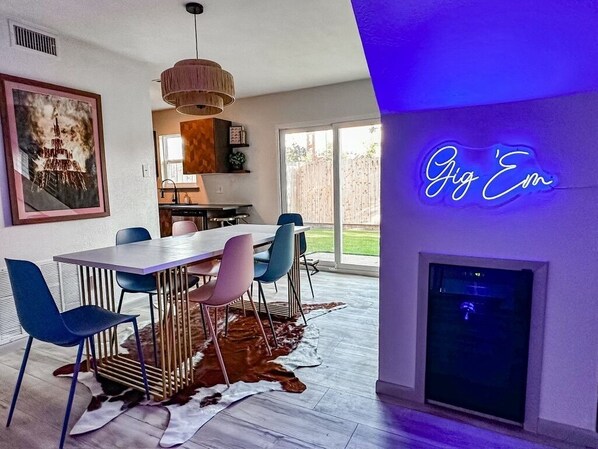 A modern dining area with a white table, colorful chairs, and a cowhide rug.