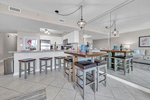 A modern kitchen with a central island, bar stools, and pendant lighting. - 🏖️🌞Pelican Beach 102 - Beach Daze | Gulf and Pool Views | 3 Pools (Destin)