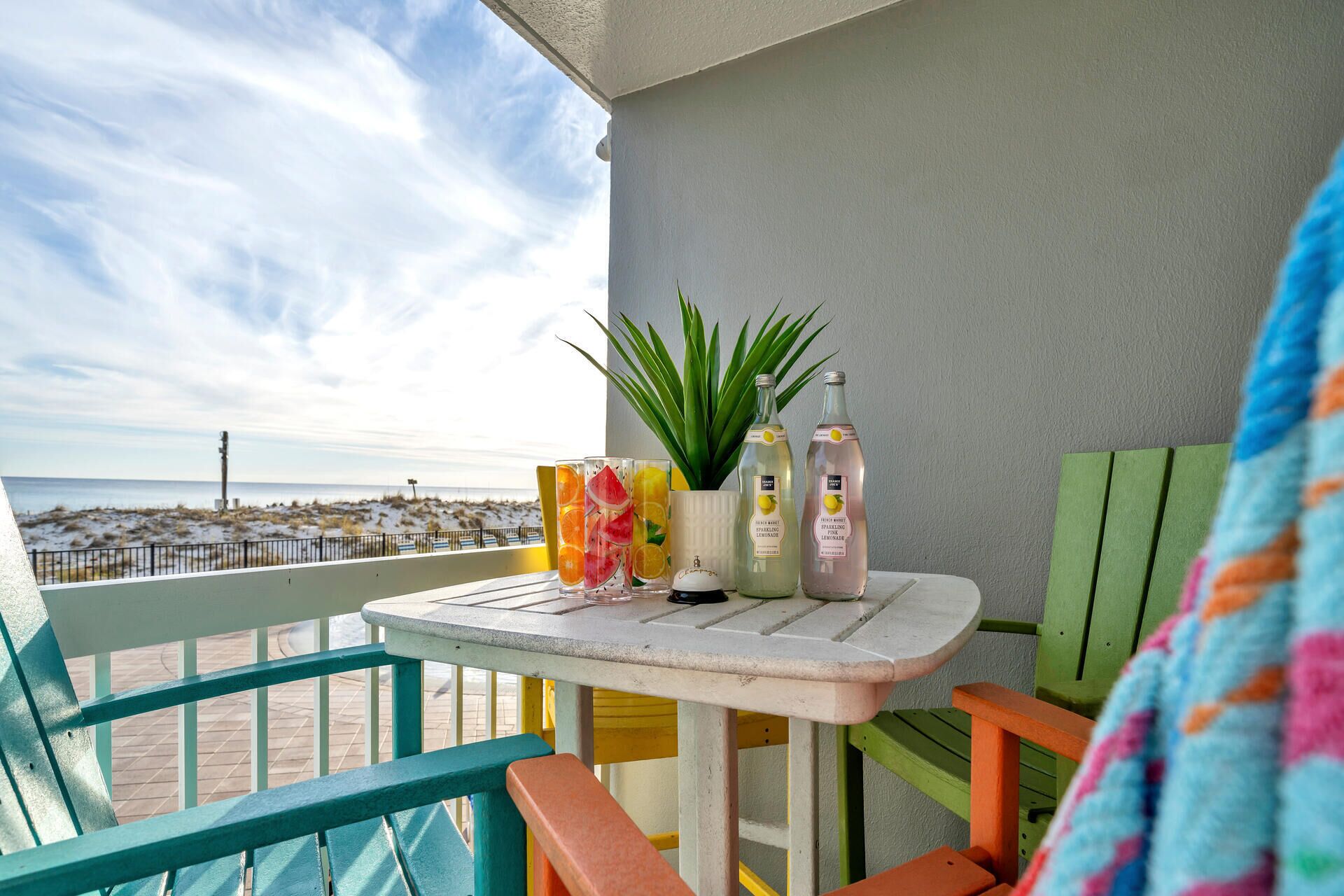 A balcony with a table, chairs, and a view of the beach.