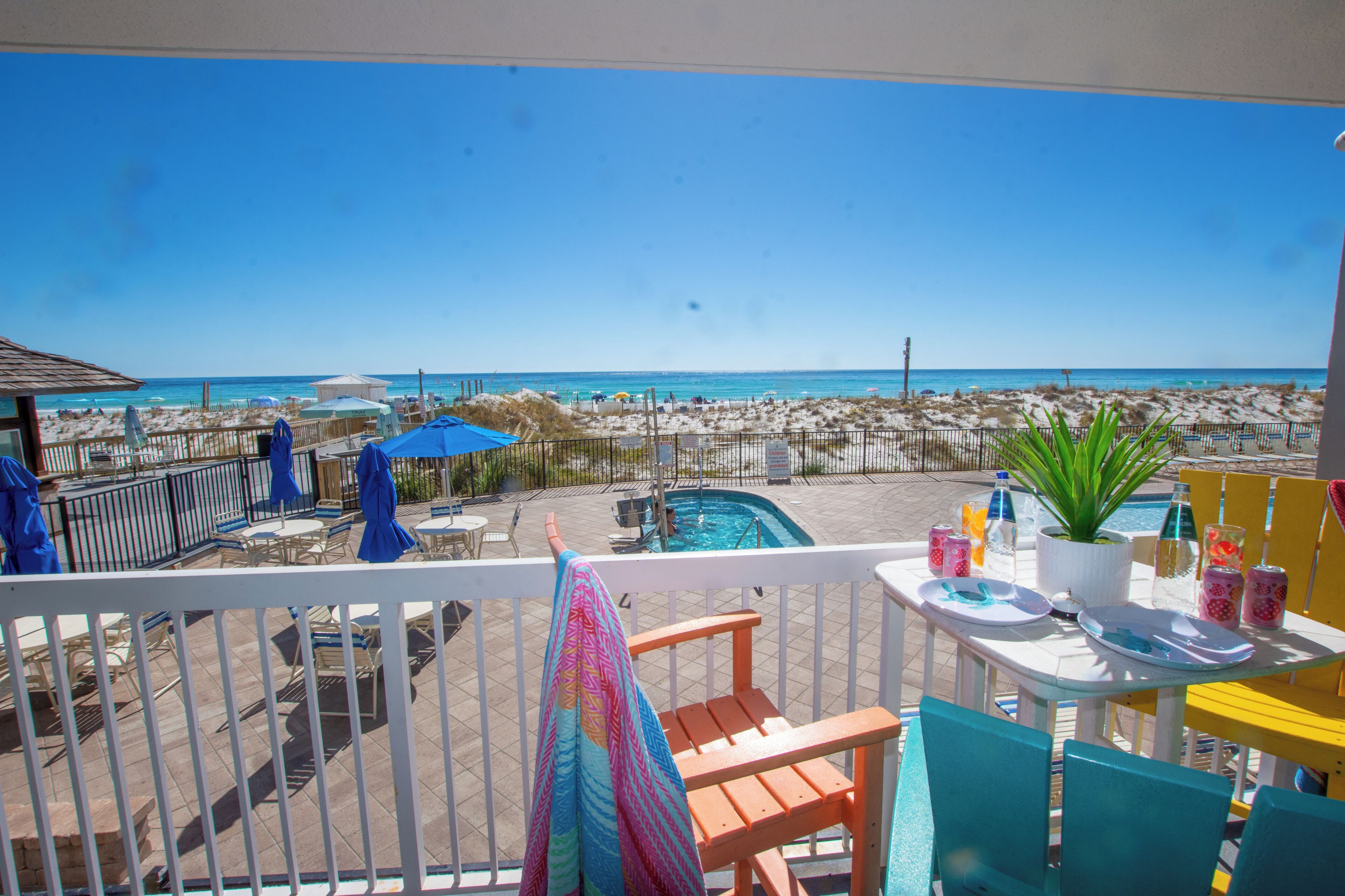Un balcón con vistas a la playa, mobiliario exterior y una piscina.