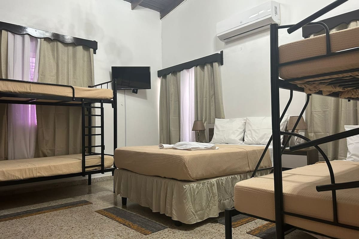 Une chambre de dortoir équipée de lits superposés, d’un lit simple, d’une télévision et d’un appareil de climatisation.
