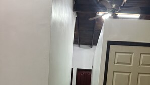 A narrow hallway with green and white walls, a tiled floor, and a closed door at the end. - Seven Days Hotel B&B (San Pedro Sula)