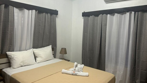 A hotel room with a bed, two pillows, a folded towel, and an air conditioning unit on the wall. - Seven Days Hotel B&B (San Pedro Sula)