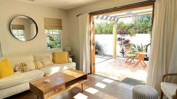 A living room with a sofa, coffee table, and a view of a garden through a sliding glass door. - Bright & Airy Culver City Home w/Garden Oasis. Walkable Location + WFH Ready! (Los Angeles)