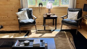 A cozy room with two leather chairs, a small table with a lamp, and a view of a forest through a large window. - Aspen Ridge-Mountain Adventure House in the Colorado Rockies-STR-0076-2026 (Fairplay)