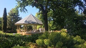 A gazebo in a lush garden with dense foliage and trees in the background. - Winton Cottage Maldon - Authentic Heritage Home. (Maldon)