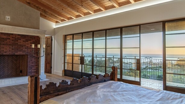 A bedroom with a large window, a fireplace, and a balcony with a view. - New Malibu Estate ~ Recording Studio, Tennis, Pool (Malibu)