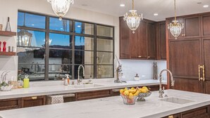 A modern kitchen with a large island, dark wood cabinets, and three crystal chandeliers. - New Malibu Estate ~ Recording Studio, Tennis, Pool (Malibu)