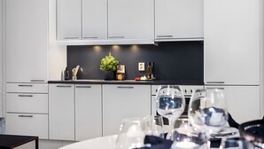 Een moderne keuken met witte kasten, een zwart aanrecht en een eethoek met een tafel gedekt voor twee personen.