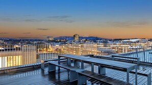 Een terras op het dak met uitzicht op een stadsgezicht in de schemering.