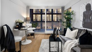 Een moderne woonkamer met een eethoek, een groot raam met uitzicht op de stad, een bank en een salontafel.