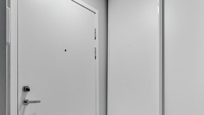 A room with a wooden floor, a white door with a handle, and a white wall.
