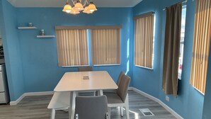 A room with a white table and chairs, blue walls, and a ceiling light fixture. - Attention Snowbirds! (Fort Myers)