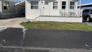 A single-story mobile home with a number 11660, a front porch with a railing, and a driveway. - Attention Snowbirds! (Fort Myers)