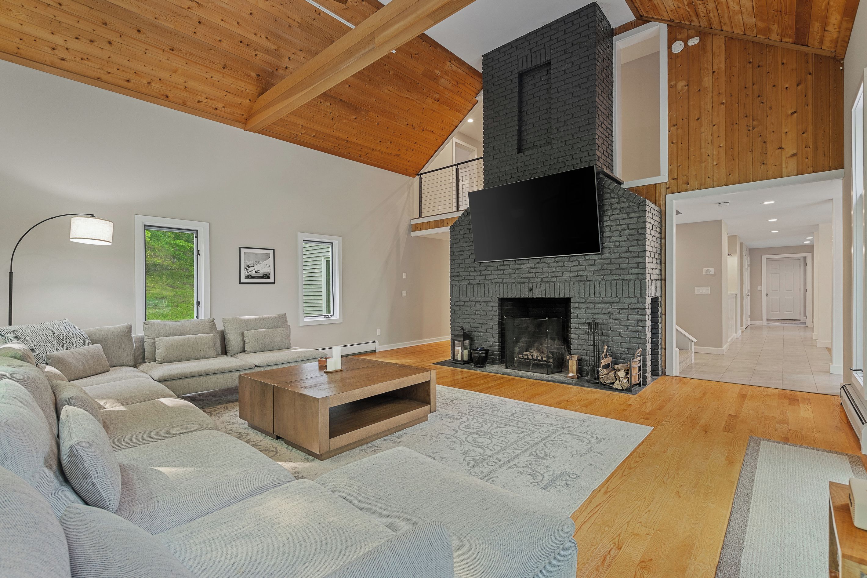 A spacious living room with a large sectional sofa, a fireplace, and a high ceiling with exposed wooden beams.