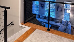 Un intérieur moderne avec un escalier menant à un espace de vie offrant une vue sur les arbres.