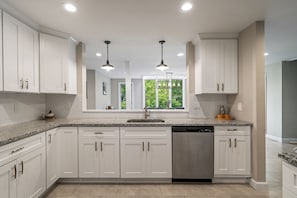 A modern kitchen with white cabinetry, granite countertops, a stainless steel dishwasher, and pendant lighting. - Hot Tub, Game Room, Pool Table | Weekend Stratton Shuttle, 5BR (Winhall)