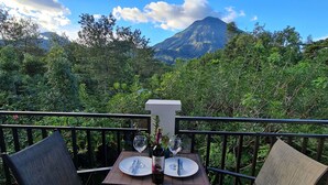 Une table avec deux chaises sur un balcon donnant sur les montagnes.