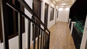 Un escalier moderne avec une rampe noire menant à un balcon également doté d’une rampe.