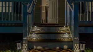 A staircase leading to a door with a glass panel, flanked by blue railings and two lantern-style lights.
