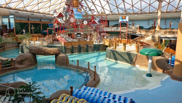 An indoor water park with a large pool, slides, and play structures.