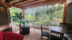 Une terrasse en bois avec une table et des chaises, un canapé rouge et une grande plante.