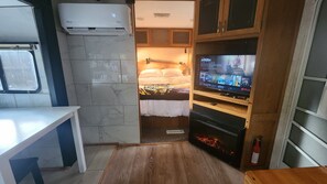 Une petite chambre comprenant un lit, un téléviseur et une petite table.
