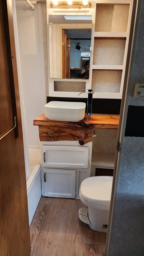 Une petite salle de bain avec un meuble-lavabo en bois, un lavabo blanc et des toilettes.