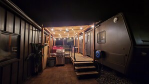 A cozy RV interior with a wooden deck, a small kitchenette, and a seating area. - Forest Cabin - Hot Tub - Fast WiFi - Fire Pit On Site (Duncan)