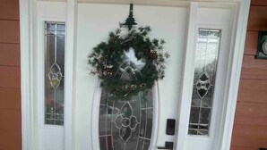 Una porta bianca con un pannello di vetro satinato e una ghirlanda sopra.