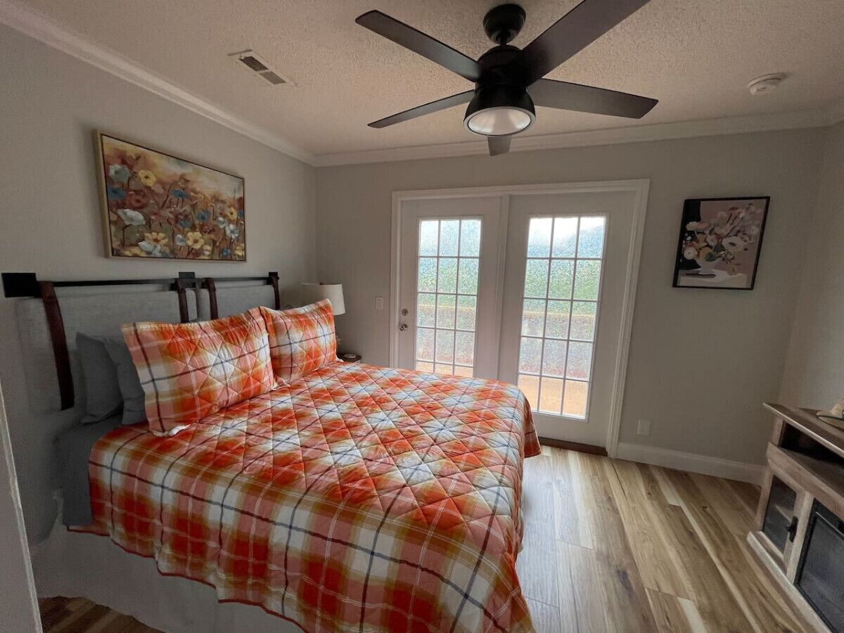 Une chambre à coucher avec un lit, un ventilateur de plafond et une porte donnant sur un balcon.