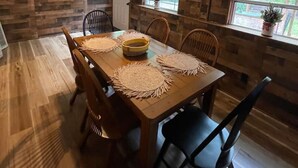 Zona pranzo con tavolo in legno, sedie e ventilatore a soffitto.