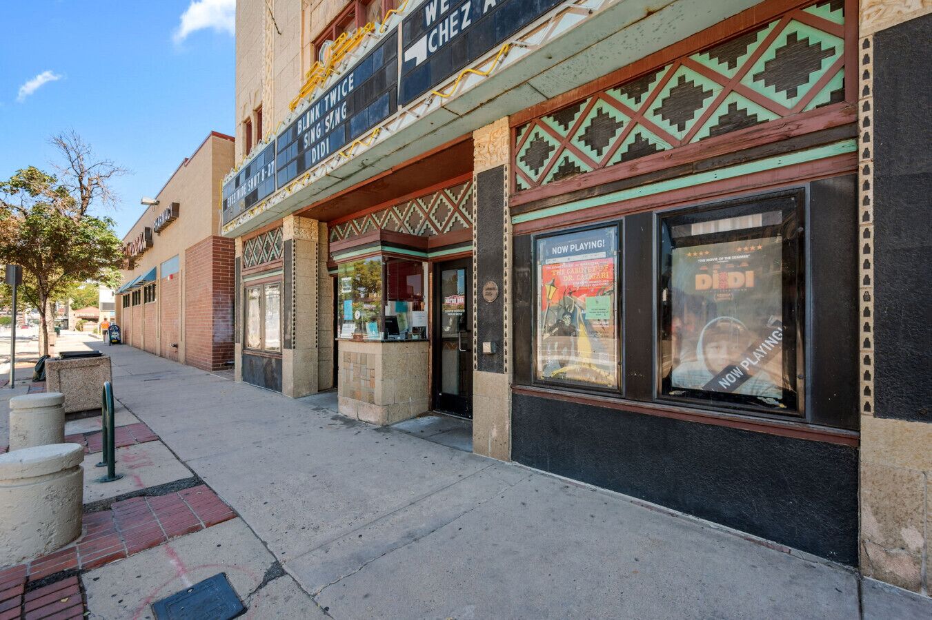 A theater with a marquee displaying movie titles and a poster for 'DIDI' playing.