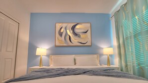 A hotel room with a bed, two bedside lamps, a wall-mounted abstract painting, and a window with curtains. - Disney World/Private Swimming Pool, 5bed/5bath 5mins away to Oasis Club
 (Davenport)