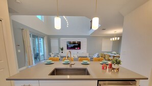 A modern kitchen with a central island, stainless steel appliances, and a dining area with yellow chairs. - Disney World/Private Swimming Pool, 5bed/5bath 5mins away to Oasis Club
 (Davenport)
