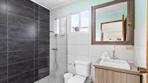 A modern bathroom with a shower, toilet, and sink. - BRAND NEW Central Modern Ground Studio with Pool (Noord)