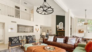 A spacious living area with a high ceiling, a fireplace, and a dining area in the background. - 6BR Pool & Game Arcade | Family + Dog Friendly (San Antonio)