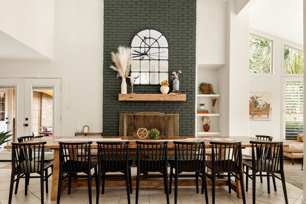 Un coin repas avec une cheminée en briques, une table en bois et des chaises noires.
