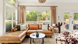 A spacious living room with a leather sectional sofa, a round coffee table, and a cactus centerpiece. - 6BR Pool & Game Arcade | Family + Dog Friendly (San Antonio)