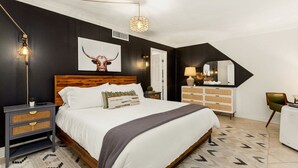 A bedroom with a large bed, a nightstand, a dresser, a mirror, and a hanging light fixture. - 6BR Pool & Game Arcade | Family + Dog Friendly (San Antonio)