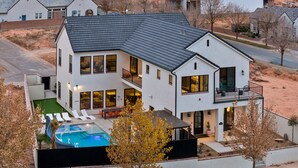 Une maison moderne à deux étages, dotée d’une piscine, de grandes fenêtres et d’un balcon.